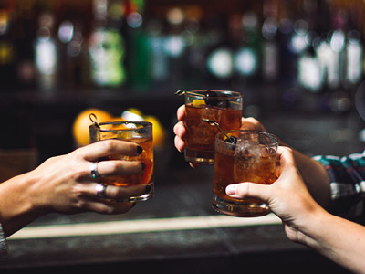 Three people clinking alcoholic drinks in a private guided bar crawl