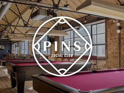 A room with three pool tables in and large windows at Pins in Liverpool