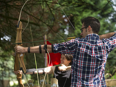 A man aiming a bow and arrow at a target in Edinburgh with Mad Max Adventures