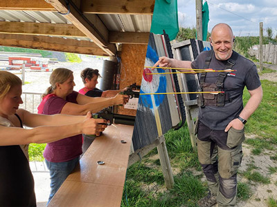 A split image of people aiming guns at targets and a man pointing at an archery target with arrows in