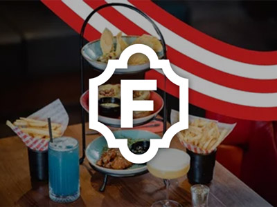 A tier of plates of food next to different cocktails at Fridays