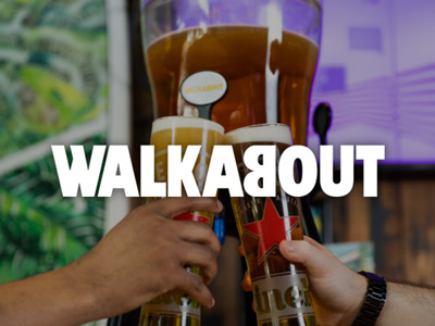 People clinking beers in front of one big pint at Walkabout