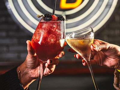 Two people clinking alcoholic drinks at bottomless brunch at Point Blank