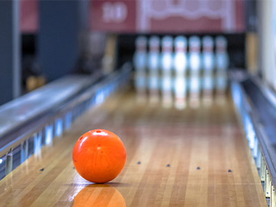An orange bowling ball heading towards pins down a bowling alley at Ten Pin Bowling in Newcastle