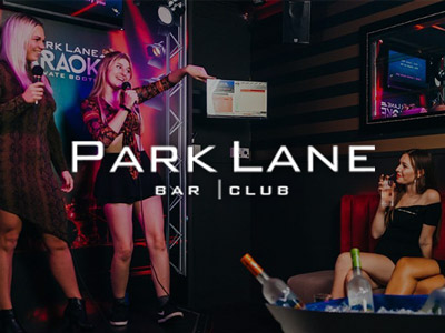 Two girls performing karaoke with other girls watching at Park Lane