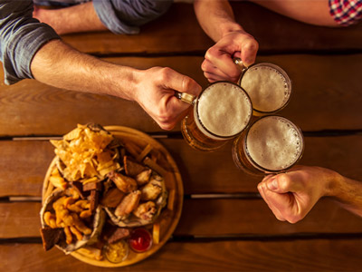 Men clinking pints of beer over food in Madrid