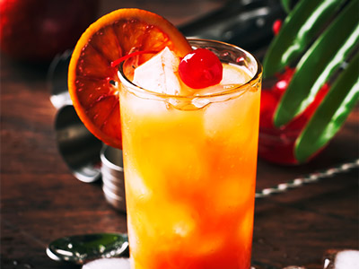 A close up of a tequila sunrise cocktail with a slice of orange in it at a Sunday Fiesta in Algarve