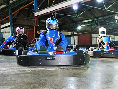Three go karts racing on an indoor circuit