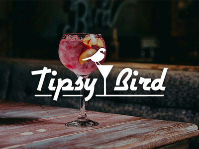 A pink cocktail with fruit in it on a table at The Tipsy Bird