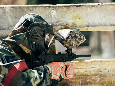 Someone dressed in camouflage, pointing a paintball gun at their target in Split