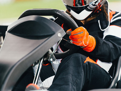 Someone racing a go kart outside with a helmet and gloves on