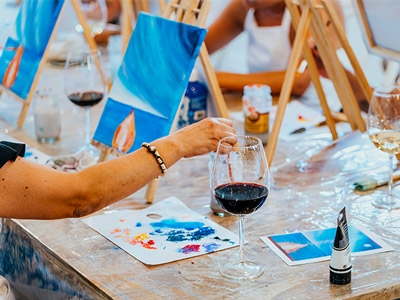 A group of people painting while drinking glasses of wine 
