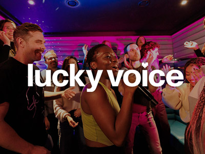 A woman performing a song at karaoke in front of her friends at Lucky Voice