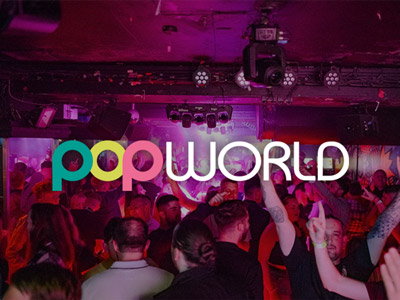 A group of people dancing under pink lighting at Popworld