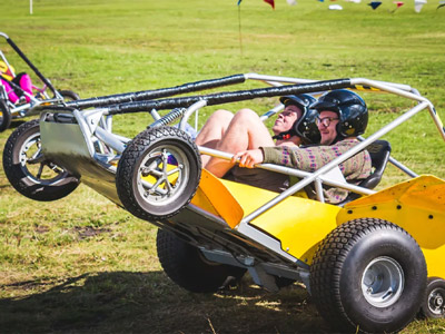 Two people in a powerturn buggy with the front wheels lifted off the ground 