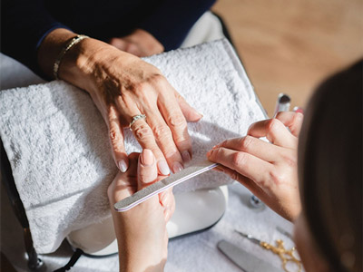 Someone filing a woman's nails as part of a manicure at Glo Pamper