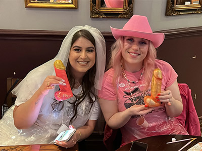 Two women posing with their painted penises in hand