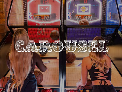 Two girls shooting basketballs into hoops at Carousel