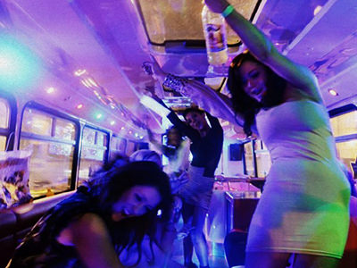 A Dublin hen group dancing inside a party bus under blue and purple lights