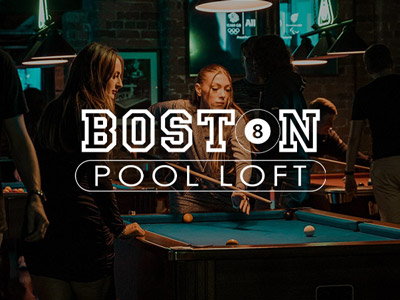 People playing pool under dark lighting at Boston Pool Loft