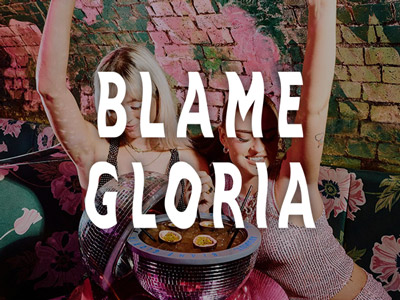 Two people posing in front of a cocktail bowl at Blame Gloria