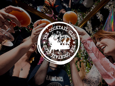 People holding up cocktail glasses in the air at The Cocktail Club