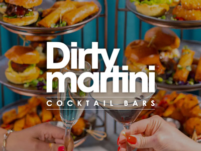 A selection of food with two people clinking their drinks in front at Dirty Martini
