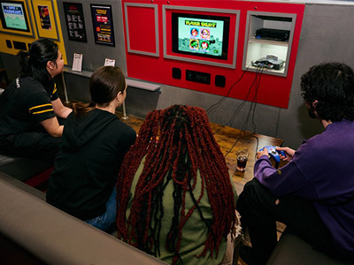 Four people sat playing a video game at an Arcade