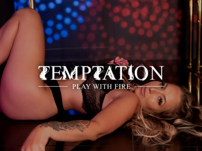 A woman dressed in black lingerie, posing in front of a pole at Club Temptation