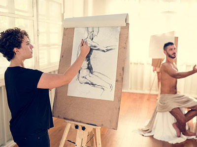 A woman drawing a semi naked man at a nude life drawing class