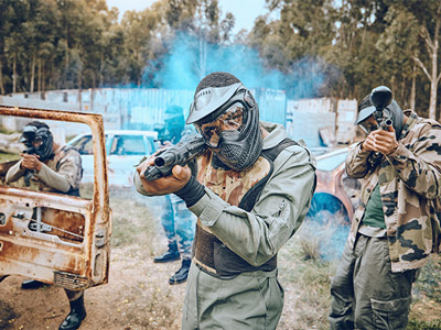 People dressed in camouflage with paintball guns in hand