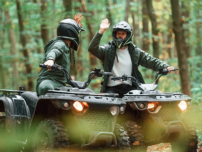 Two men quad biking through a forest