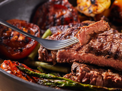 A fork holding up a piece of steak at a stag dinner
