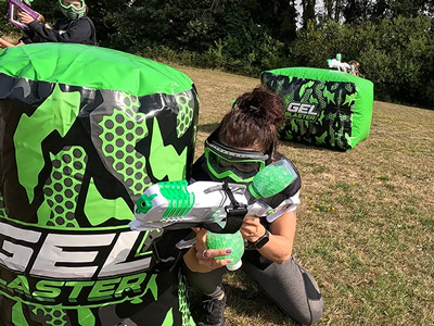 A woman hiding behind an inflatable defence whilst playing Gel Blaster 