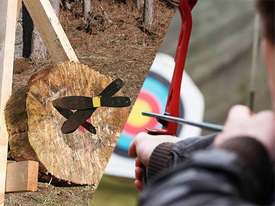 A split image of knives stuck in a wooden log and a person aiming a bow and arrow