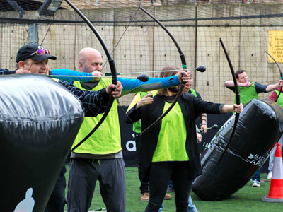 A stag group firing bows and arrows as a part of a battlezone archery session 