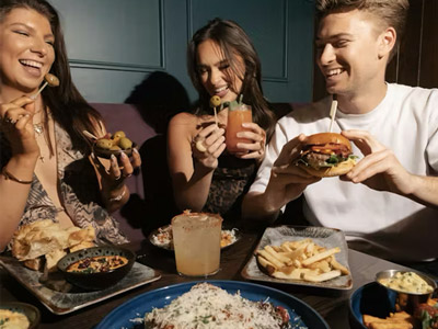 Two women and a man enjoying some food at Manahatta 