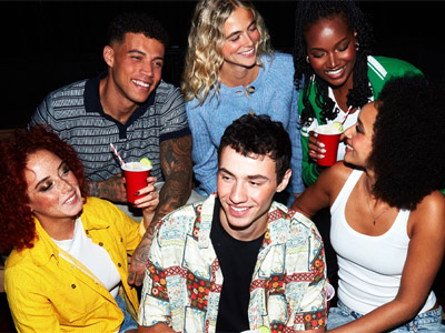 A mixed gender group of people who are drinking out of red cups 