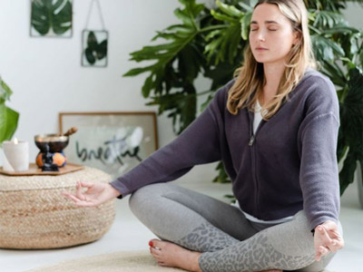 A woman sat cross legged on the floor with her eyes closed