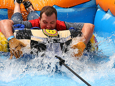 A man lying on his front and holding an inflatable surrounded by water as part of a stag do in Manchester