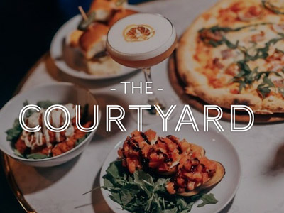 Several dishes of food with The Courtyard layered over it 