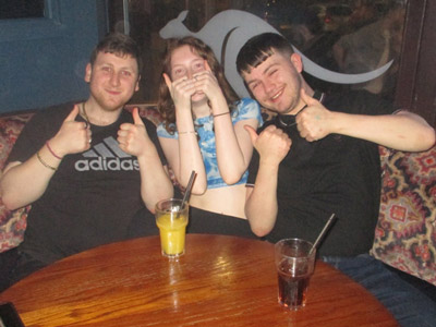 Two men and a woman sat at a booth at Walkabout all doing double thumbs up with drinks sat on the table in front of them 