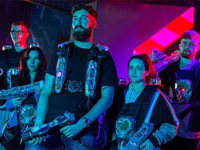 A mixed gender group holding their laser packs and guns ready to play 