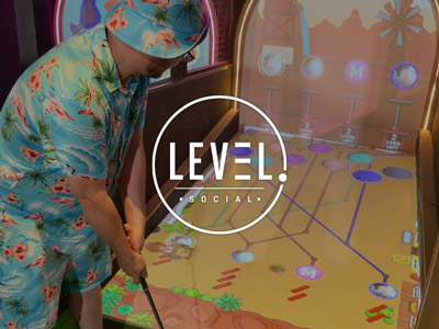 A man on a stag do in a Hawaiian outfit playing virtual golf 