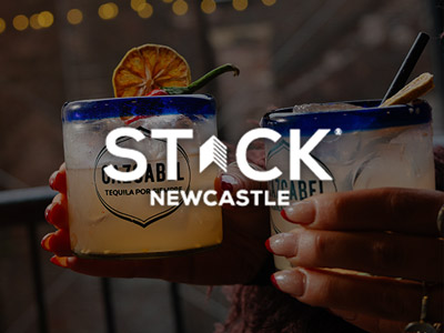 Someone holding two cocktails with the STACK logo layered over it 
