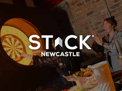 Some women playing darts with the STACK logo layered over it