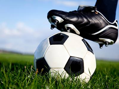 Close up of a man's football boot on top of a black and white football