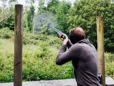 Someone aiming a gun at their clay pigeon target 