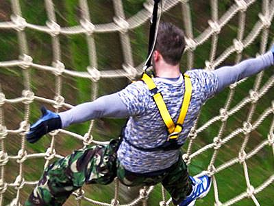 Close up of a man climbing a rope ladder