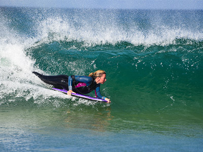 A woman bodyboarding a wave in Newquay